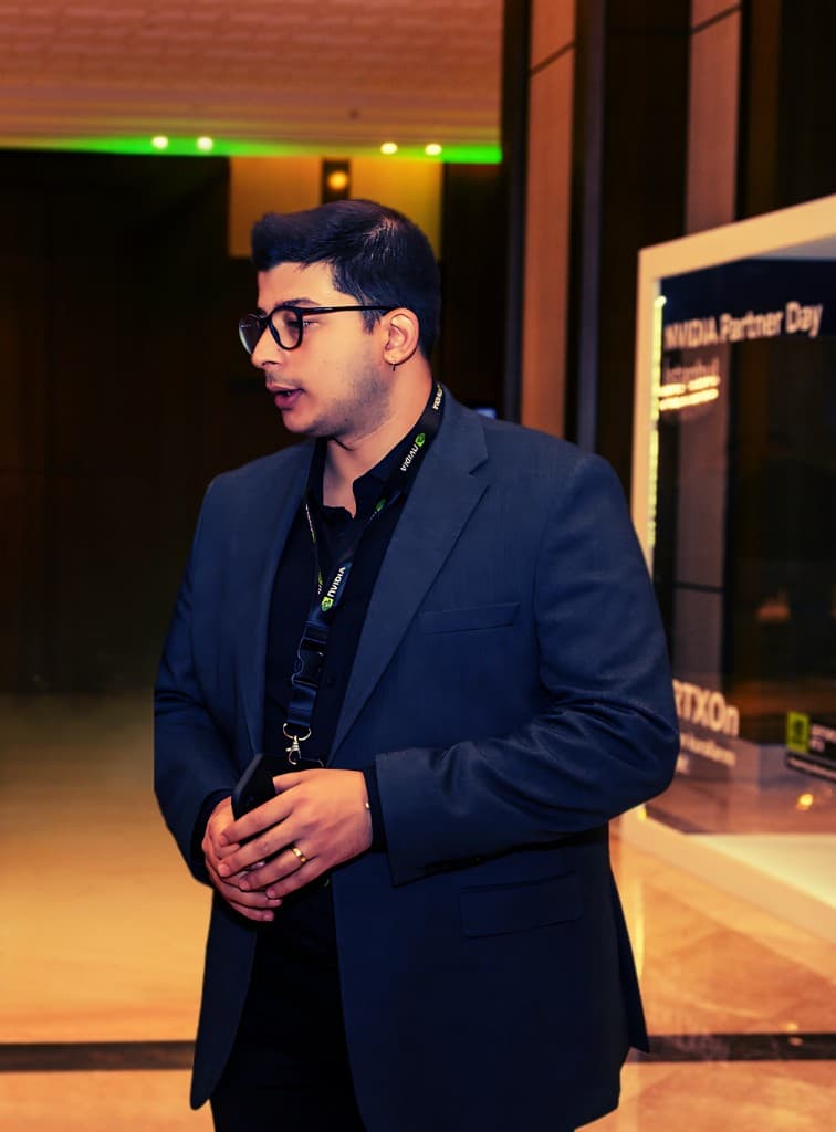 Boğaç Davut, NVIDIA Partner Day etkinliğinde koyu takım elbise ve gözlükle